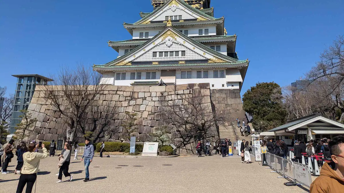 Guide and small group beside the great stone wall of Osaka Castle on a guided castle tour, Osaka Japan